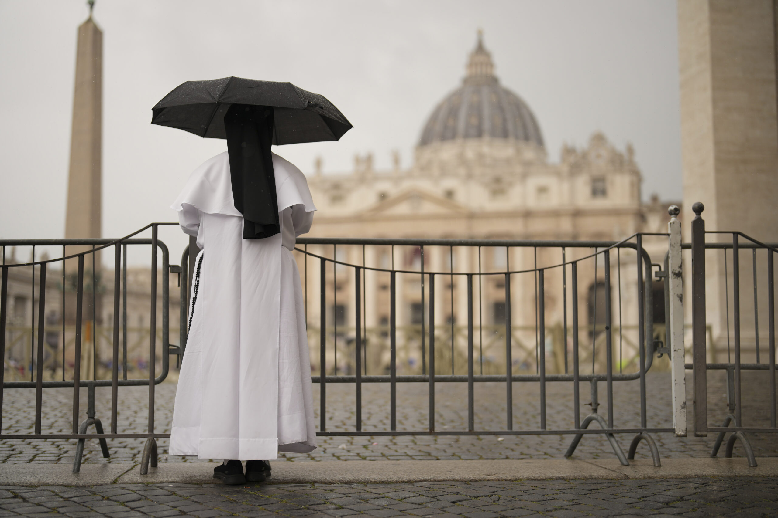 A nun shelters from the rain as she follows a final Mass