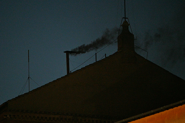 This photograph shows black smoke rising from the chimney of the Sistine Chapel
