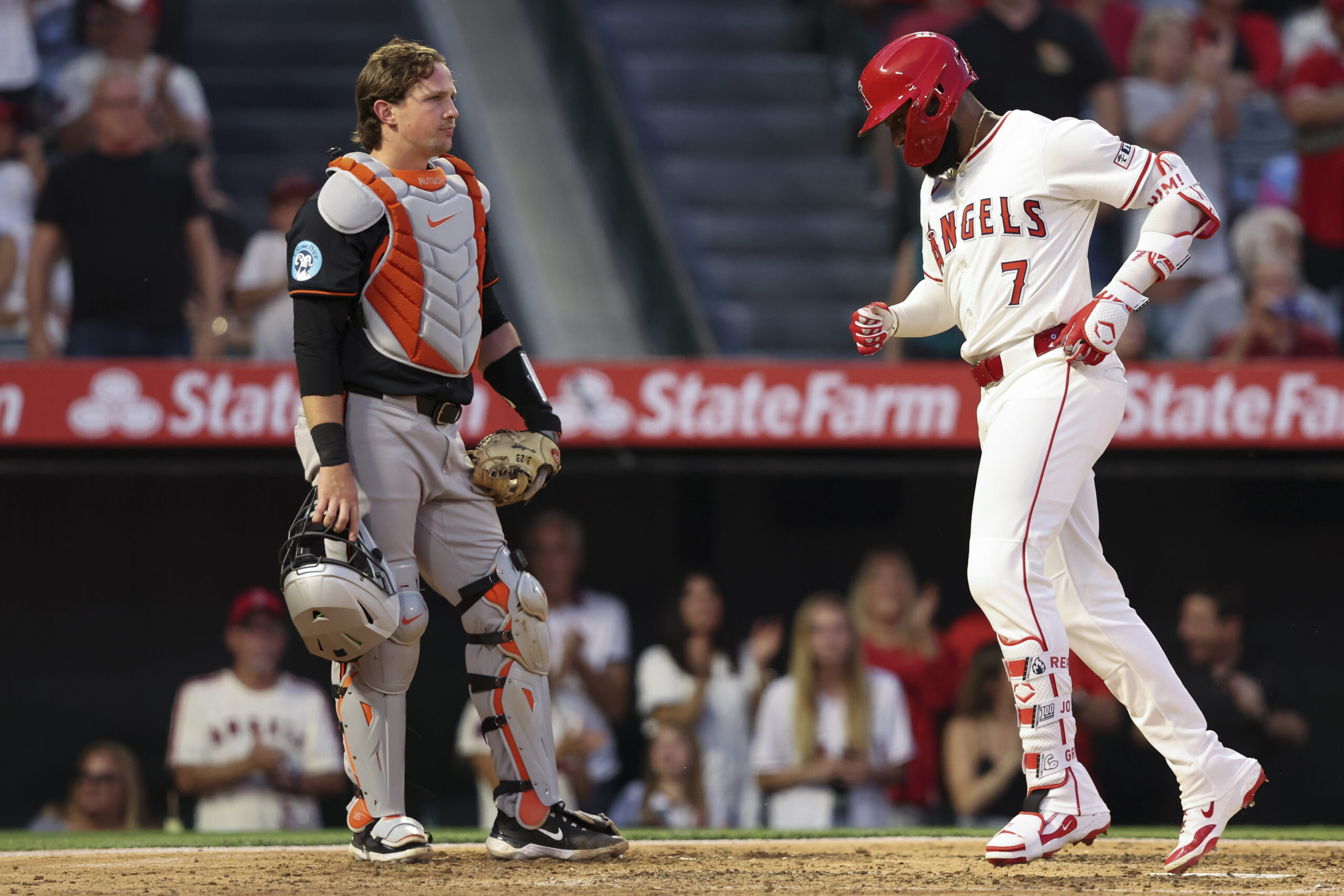 The Angels' Jo Adell reaches home plate after hitting a...