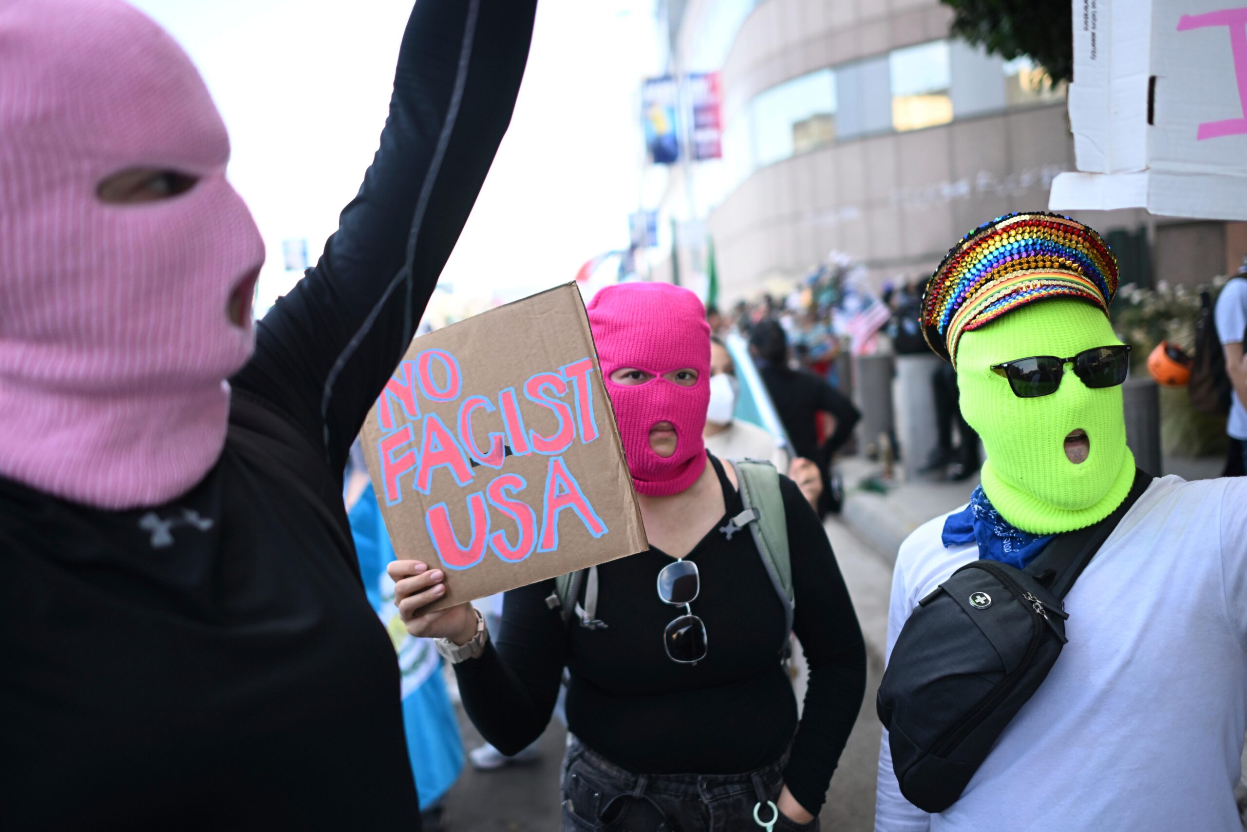 Demonstrators wearing masks hold signs outside the Federal Building during...