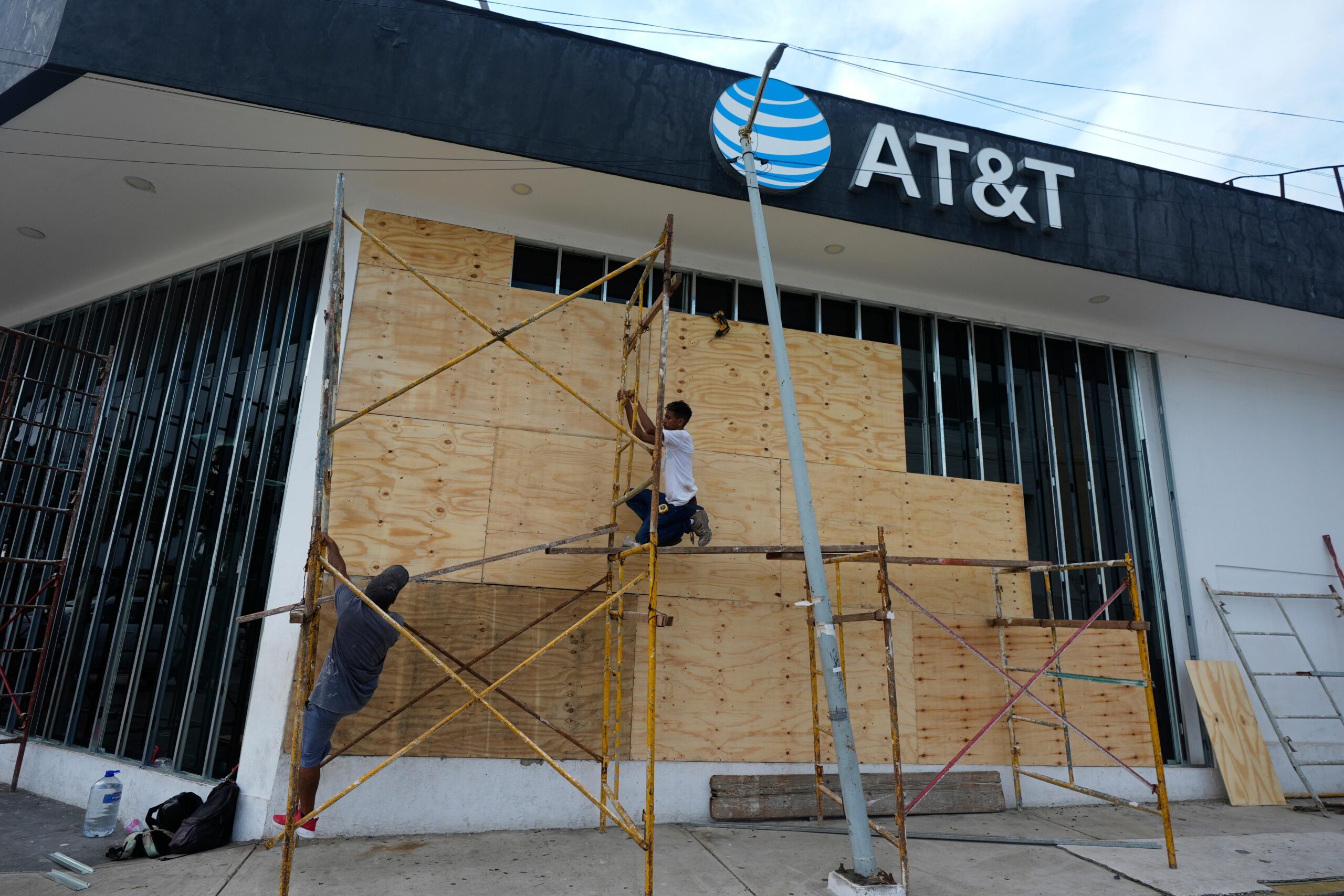 Workers board up a storefront as they prepare for the...