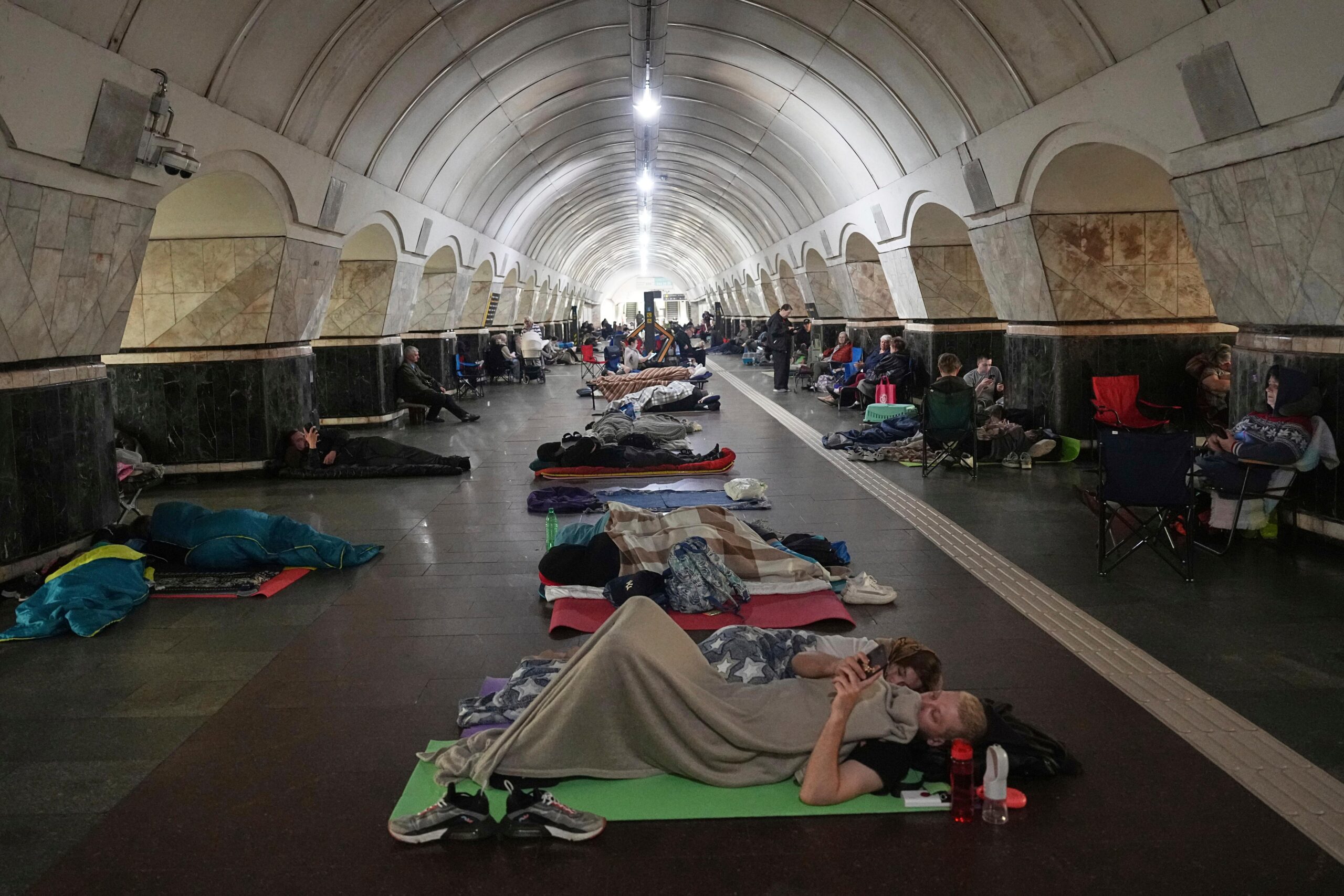 People rest in a metro station, being used as a...