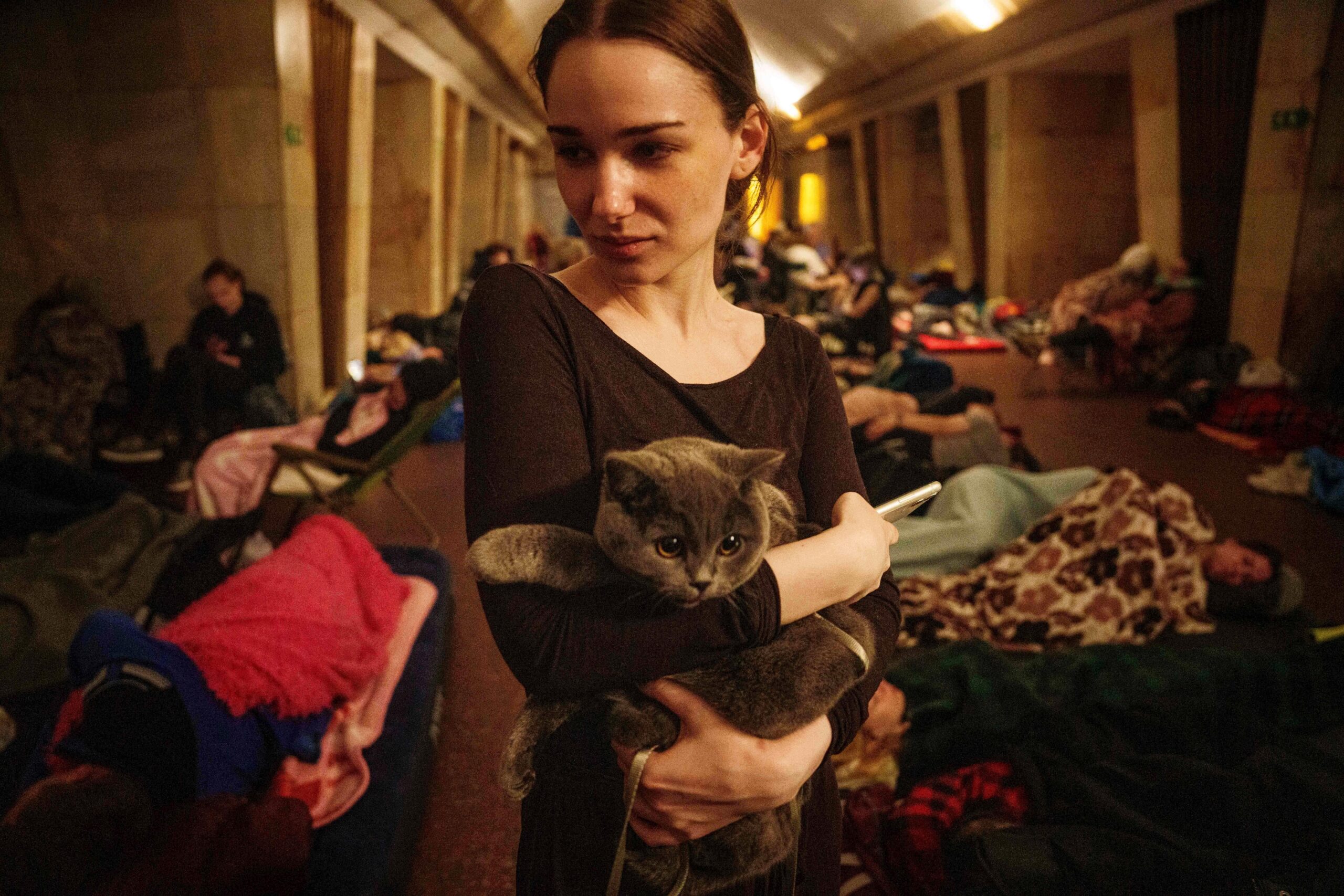 Maria, 25, holds a cat on the platform of a...