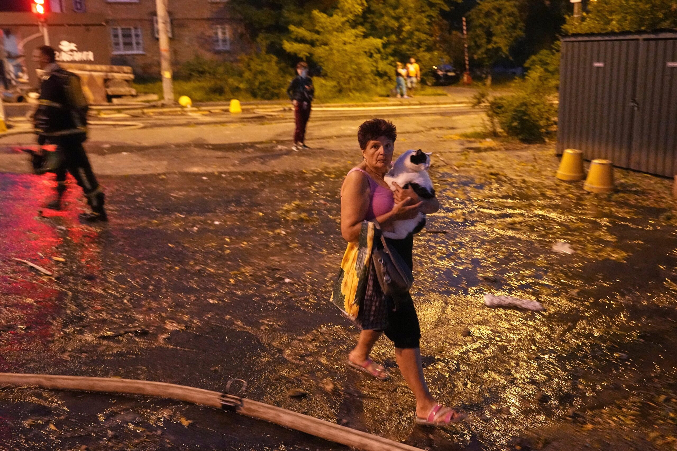 A woman carries her cat as she walks on a...