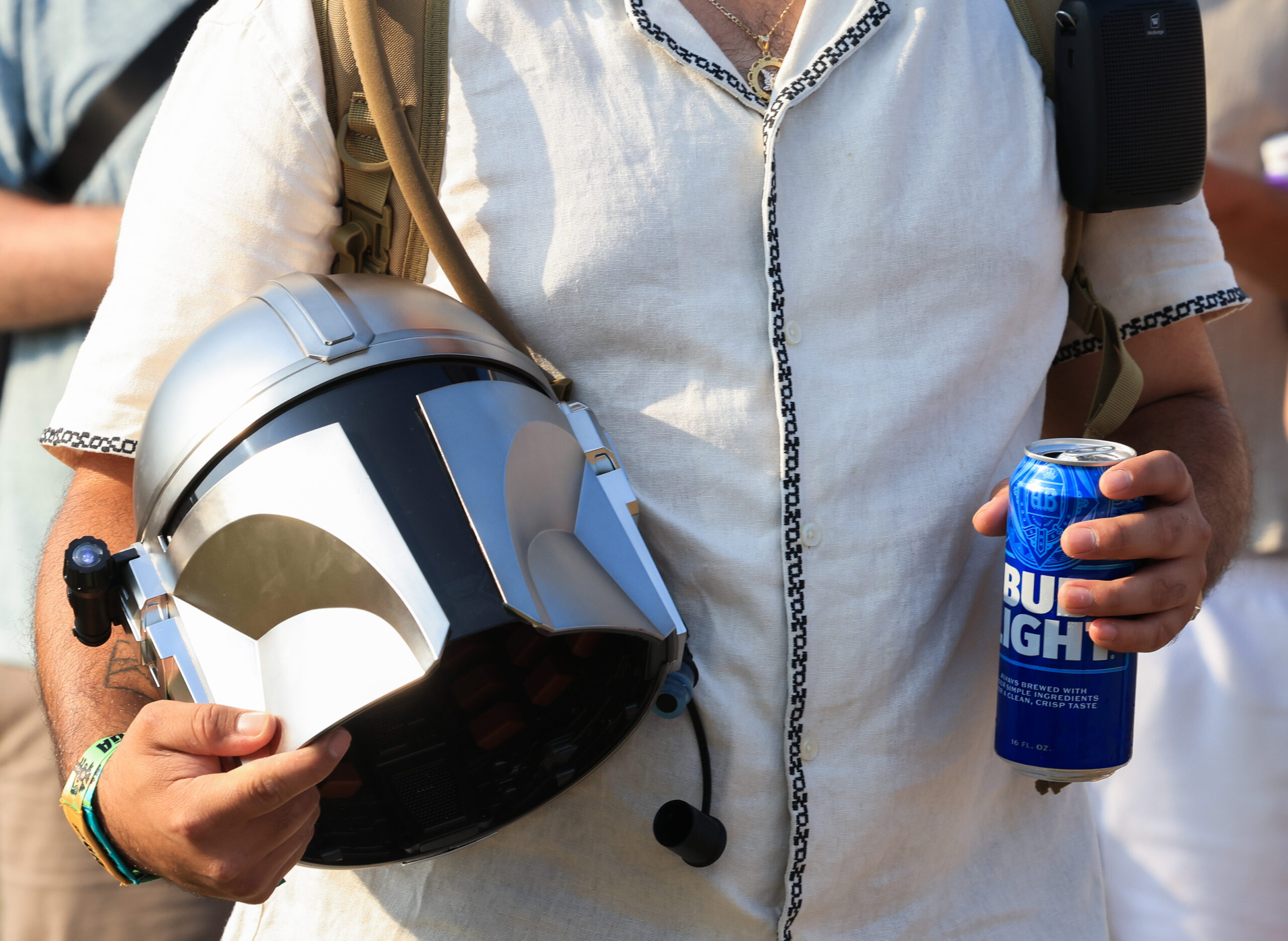 A festival attendee holds a Mandalorian helmet and a can...