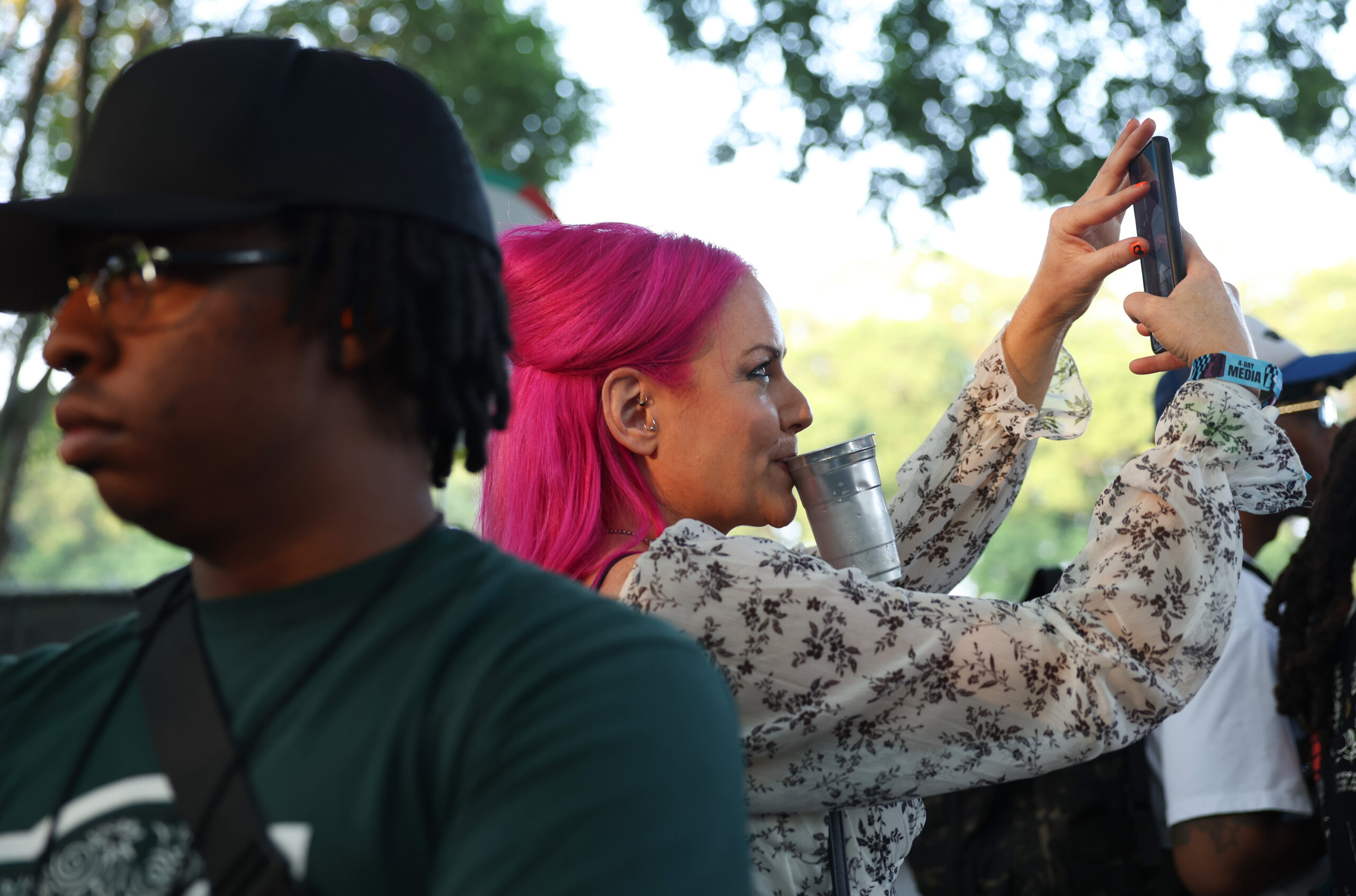 A festival attendee holds a drink cup with her teeth...