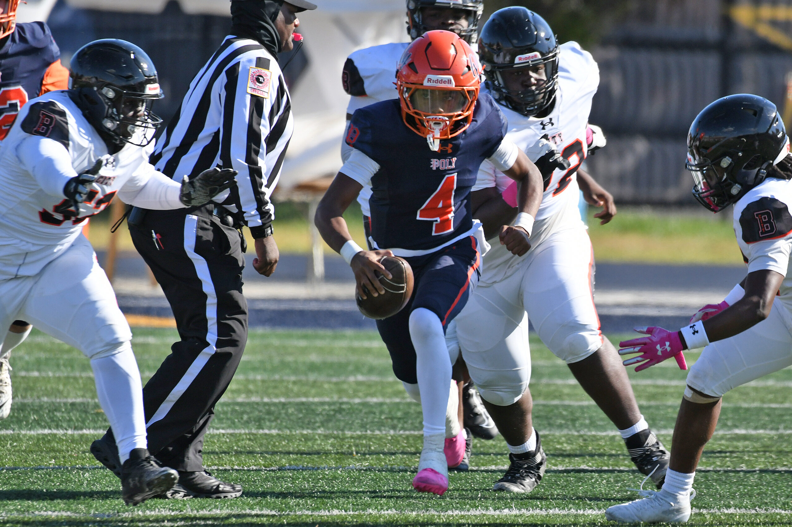 Poly quarterback Troy Brown Jr. runs between City defenders in...
