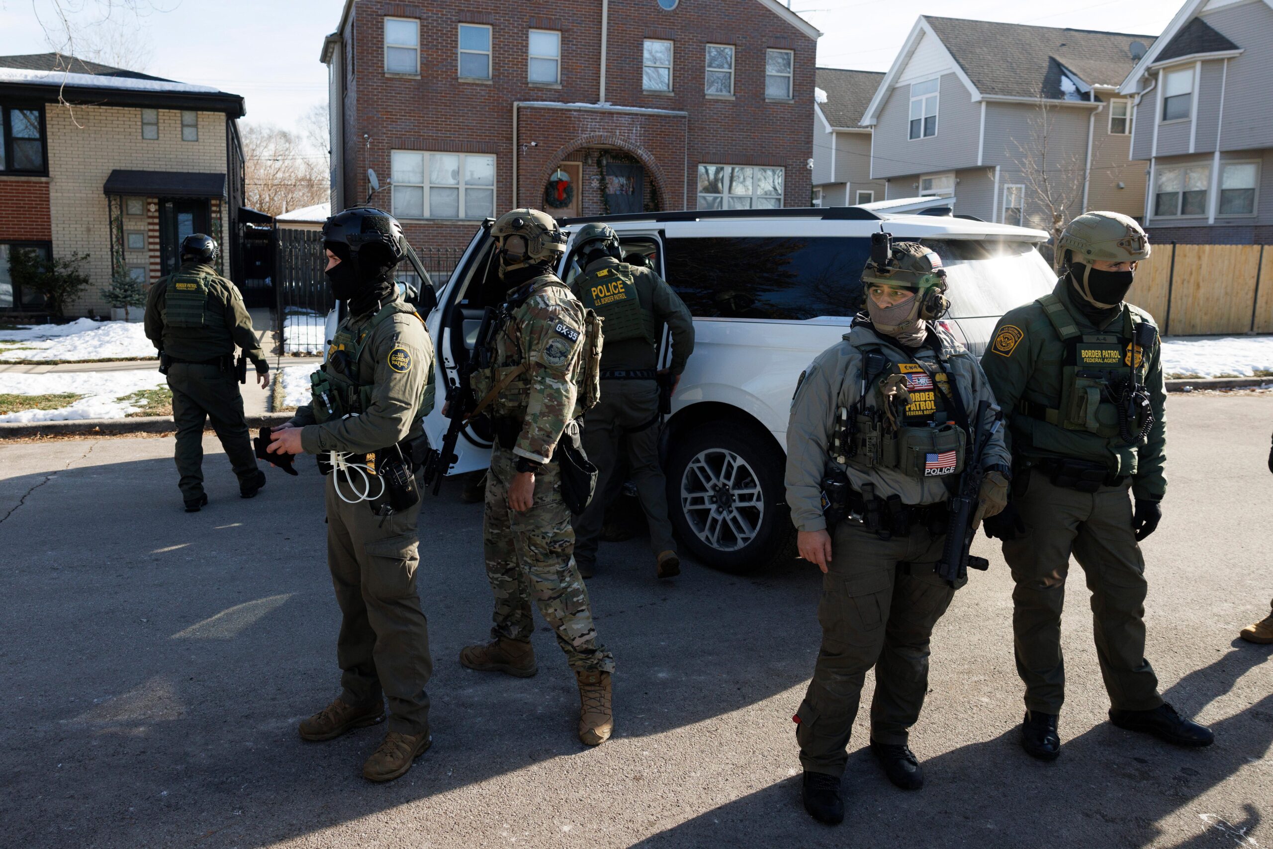 Federal immigration enforcement agents stand guard in front of their...