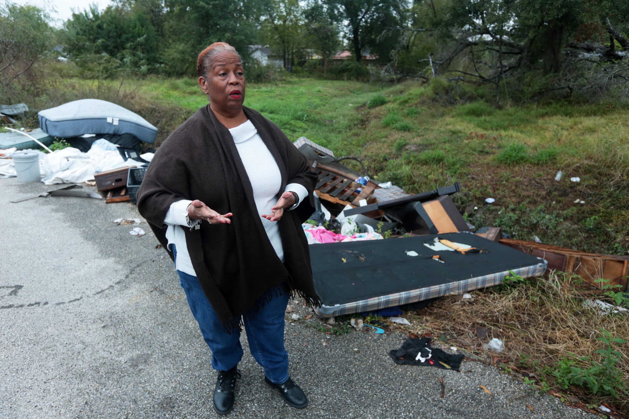 Huey German-Wilson, Trinity-Houston Community President, is interviewed near large piles...